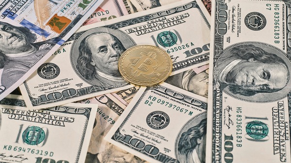 Gold crypto coin lying on US dollar bills