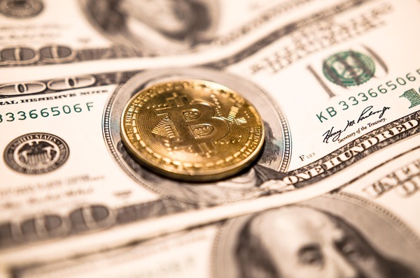 Gold Bitcoin coin on US dollar banknotes