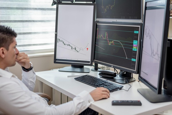 Trader watching price charts on several monitors
