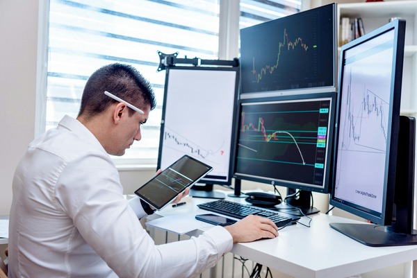 Trader working at a desk with multiple chart monitors