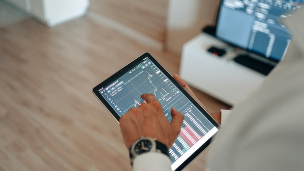 Hand tapping a market chart on a tablet