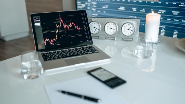 Laptop showing a candlestick chart on a white table