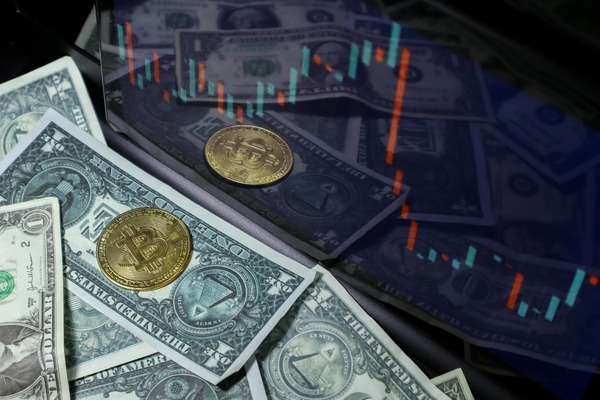 Coins on dollar bills beside a candlestick chart