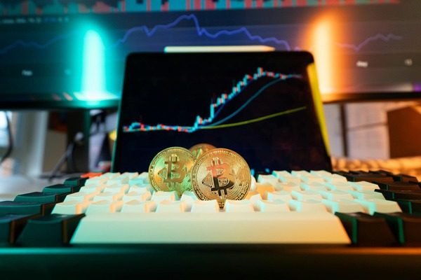 Crypto coins on a keyboard in front of a chart on a monitor