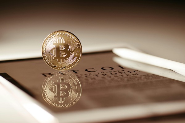 Bitcoin coin standing on a reflective tablet