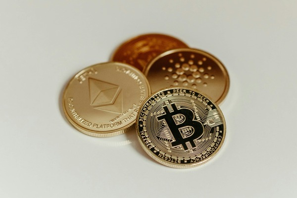 Ethereum, Cardano and Bitcoin coins on a white surface