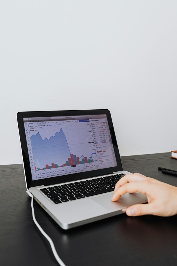 Hand using a laptop with a market chart on screen