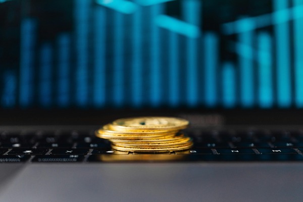 Stack of gold coins in front of a blurred chart
