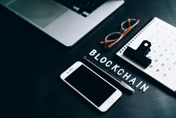 Phone, glasses and blockchain letter tiles on a dark desk