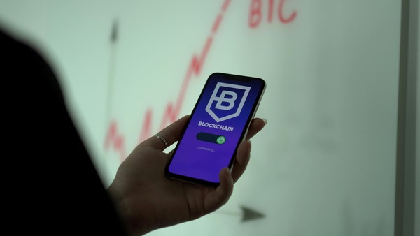 Hand holding a phone with a blockchain app screen