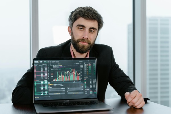 Man sitting behind a laptop with trading charts