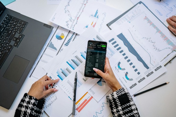 Hands holding a phone over printed charts