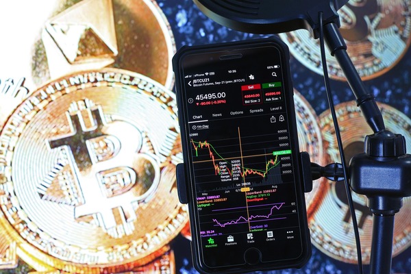 Phone with a trading chart in front of Bitcoin coins