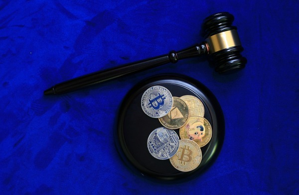 Judge gavel beside crypto coins on a blue background