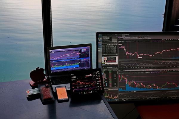 Trading monitors on a desk by the sea at dusk