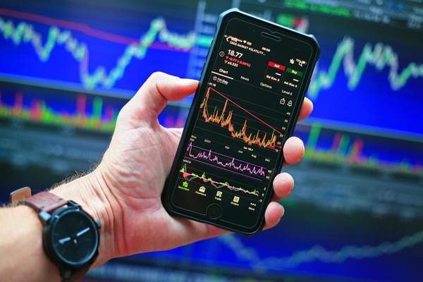 Hand holding a phone with a trading chart