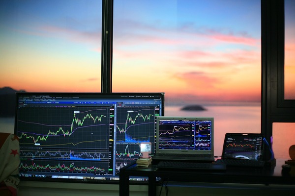 Monitors with charts in front of a sunset window